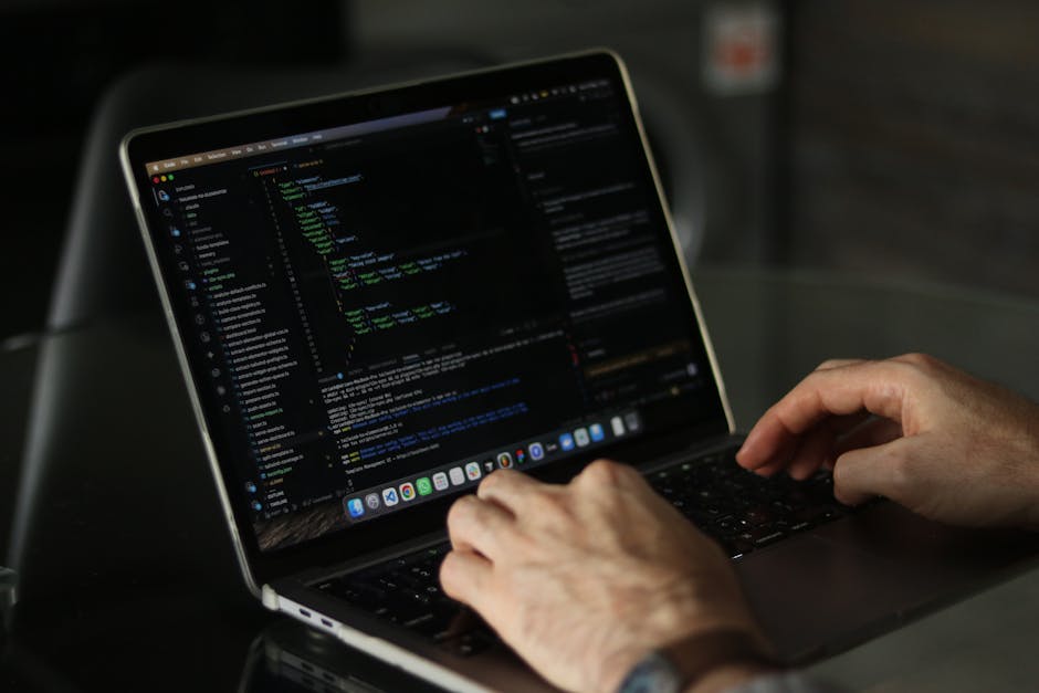 A laptop positioned on a desk displays a coding environment on the left side of the screen and a large, orange calculator interface on the right side. The coding window shows lines of HTML or CSS code